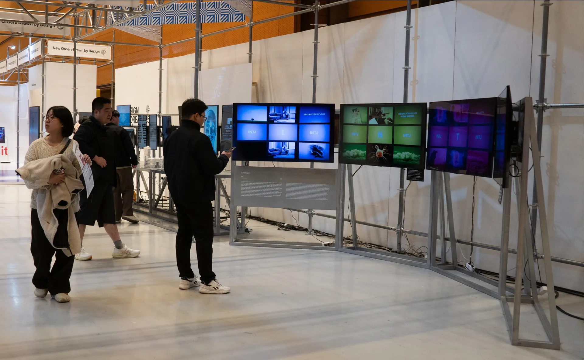 Visitors at the Ω installation of four screens arranged in an arc in the exhibition. Artwork by Jeanyoon Choi.