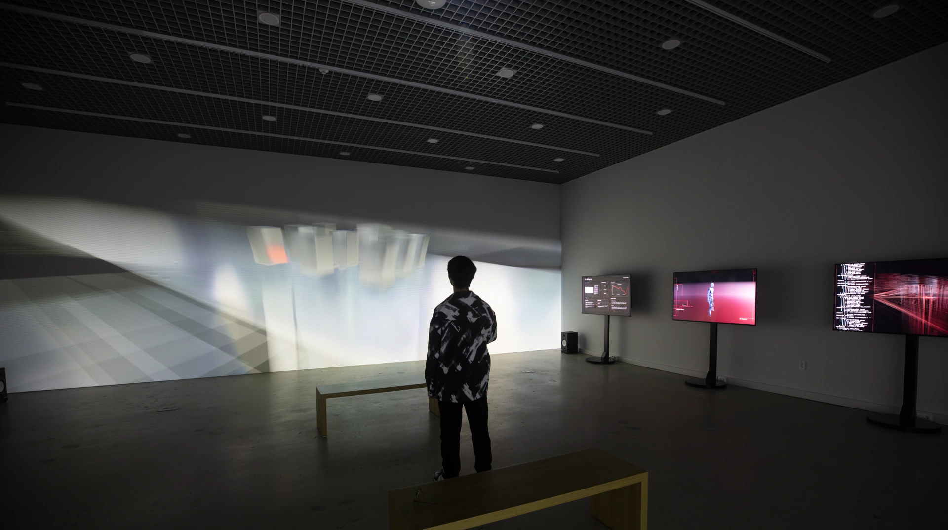SoTA: visitor facing the installation as white projected forms cross the gallery. Artwork by Jeanyoon Choi, Euan Kang, SeJoon Park, Minhyeok Seo, Prof. Yiyun Kang.